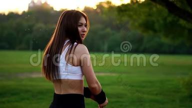 年轻漂亮的女人跑步时在公园听音乐。 带耳机的微笑运动女孩的肖像